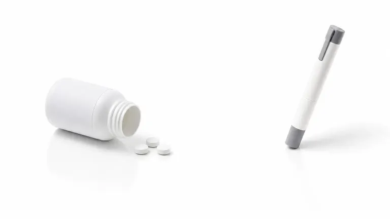 A white pill bottle with tablets facing an injection pen on a clean white background